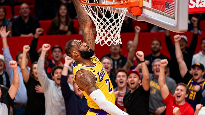 NBA常规赛中，湖人队球员在斯台普斯中心完成一记势大力沉的单手劈扣，篮球即将穿过篮筐的瞬间被高速相机捕捉，观众席上一片沸腾